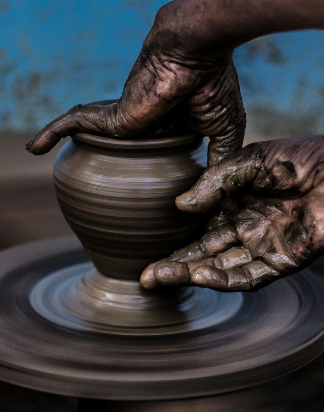 Hands shaping a clay pot on a potter's wheel