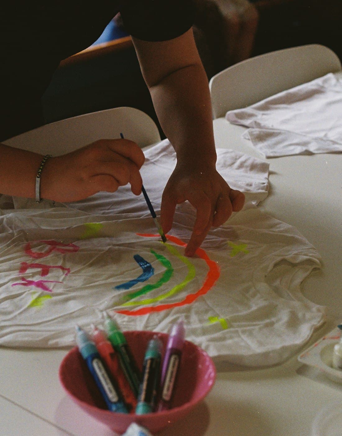 Hands painting a colourful design onto fabric
